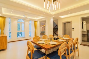 Un coin repas avec une table en bois dressée pour quatre personnes, entourée de chaises en osier avec des coussins bleus.