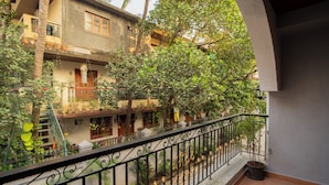 Un patio con balcón, plantas en macetas y un edificio de varios pisos.
