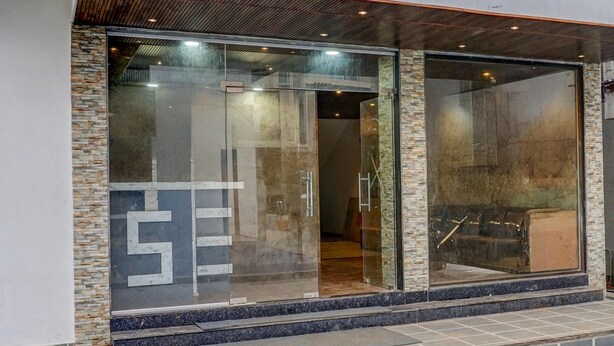 A modern building entrance with glass doors, stone accents, and a visible interior staircase.