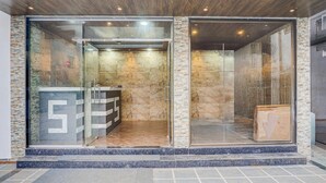 A modern building entrance with glass doors, stone walls, and a visible number '5' on the left.
