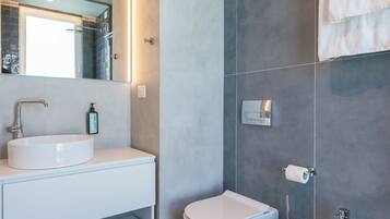 A modern bathroom with a white sink, bidet, and towel rack.