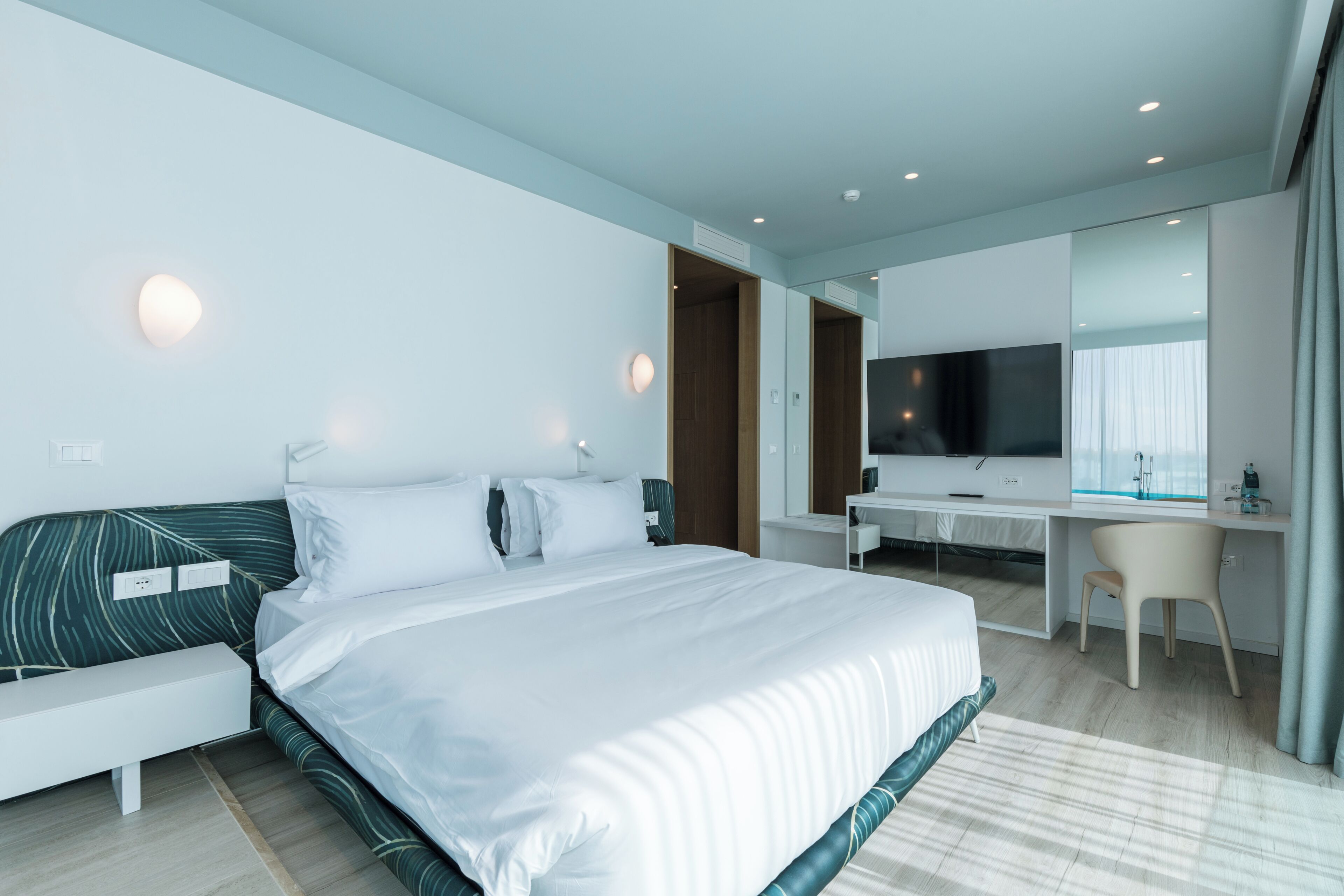 Habitación de hotel moderna con una cama grande, un escritorio, una silla y un televisor.