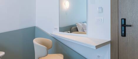 A modern bathroom with a mirror, a chair, and a wooden door.