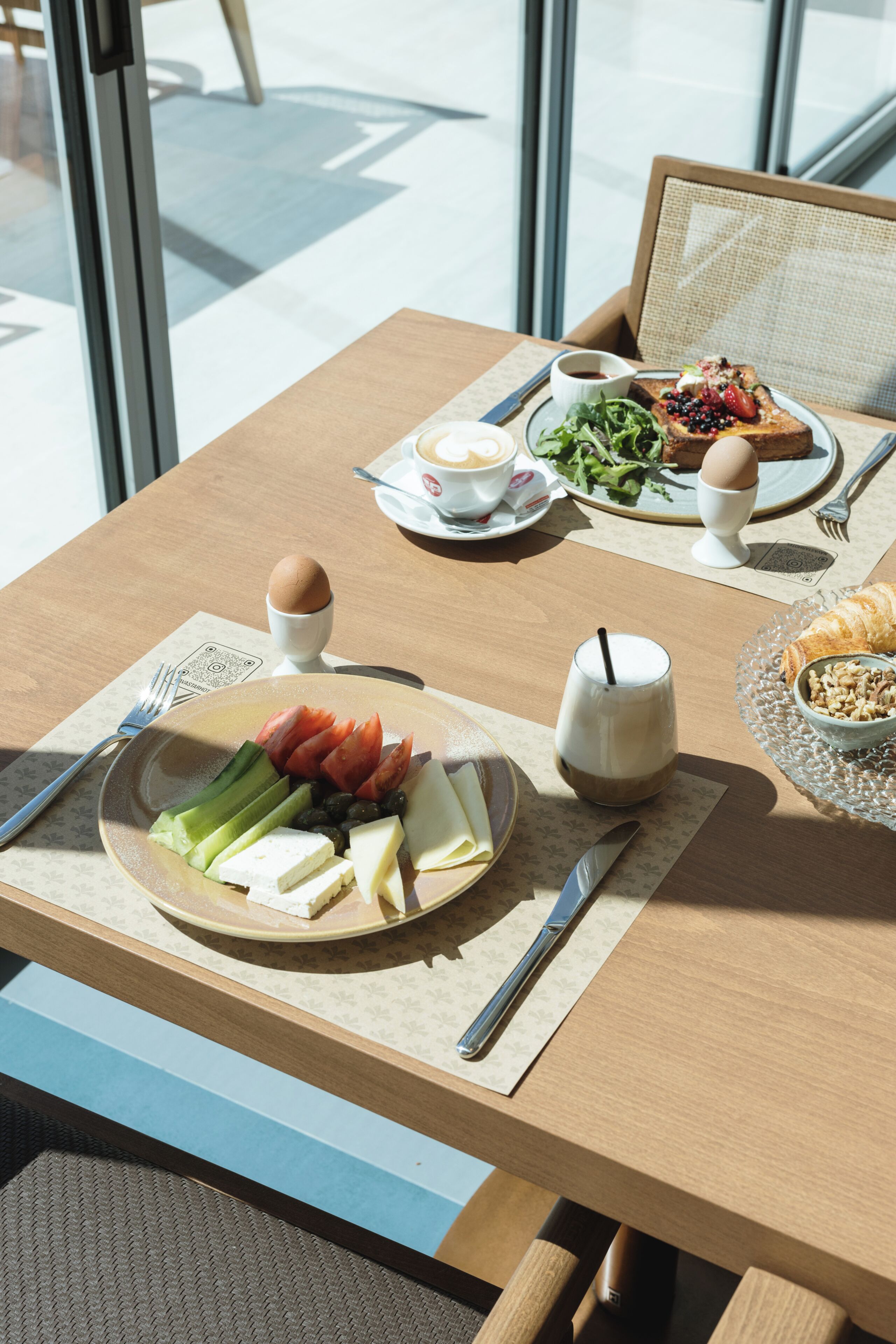 A dining table with plates of food, cutlery, and a cup of coffee.