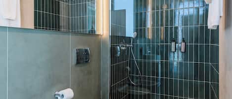 Un baño moderno con un bidé, un inodoro, una cabina de ducha de vidrio y un perchero para toallas.