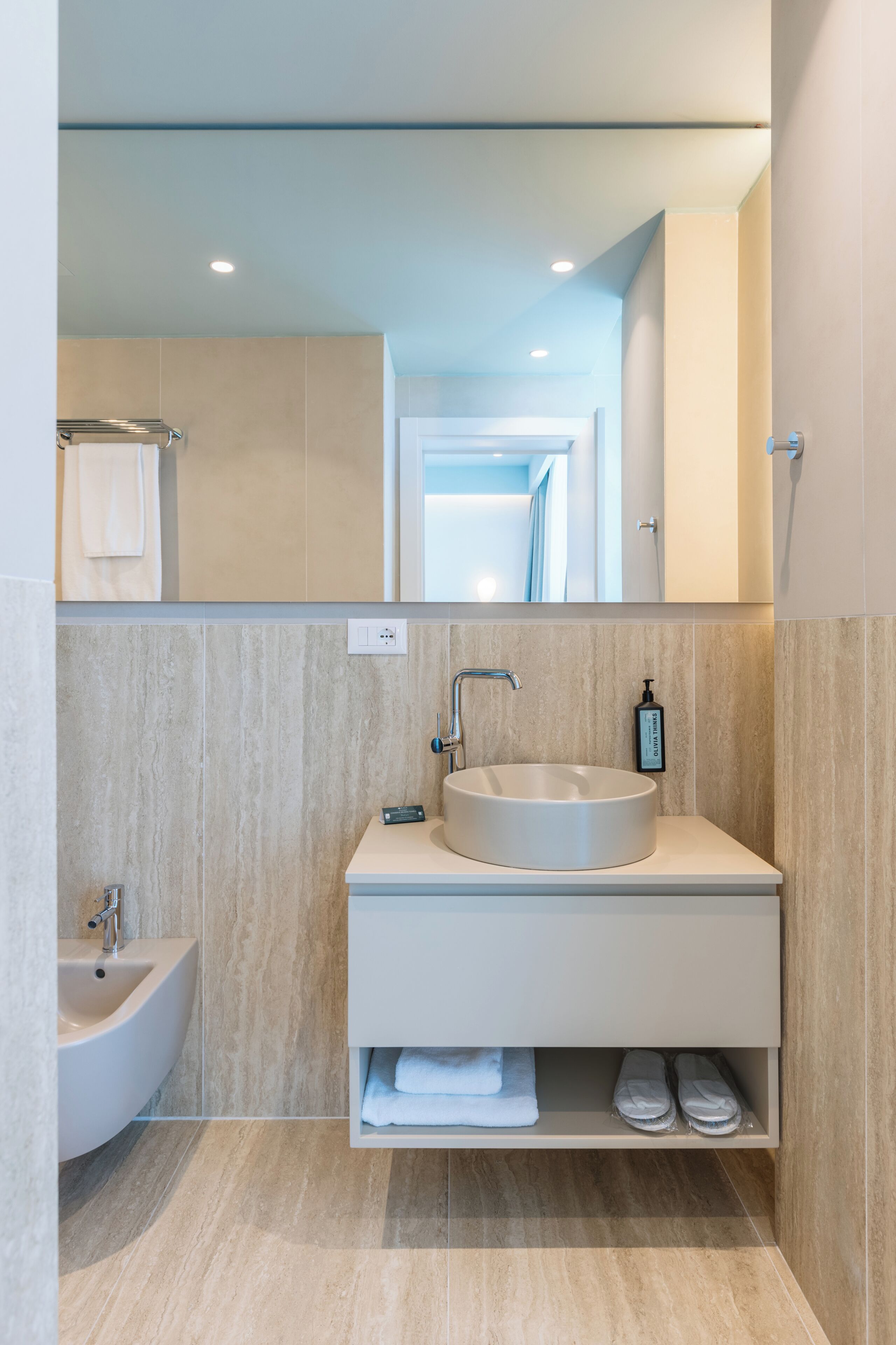 A modern bathroom with a round sink, a bidet, and a mirror above the vanity.