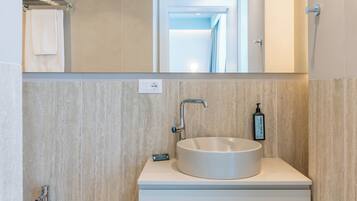 A modern bathroom with a round sink, a bidet, and a mirror above the vanity.