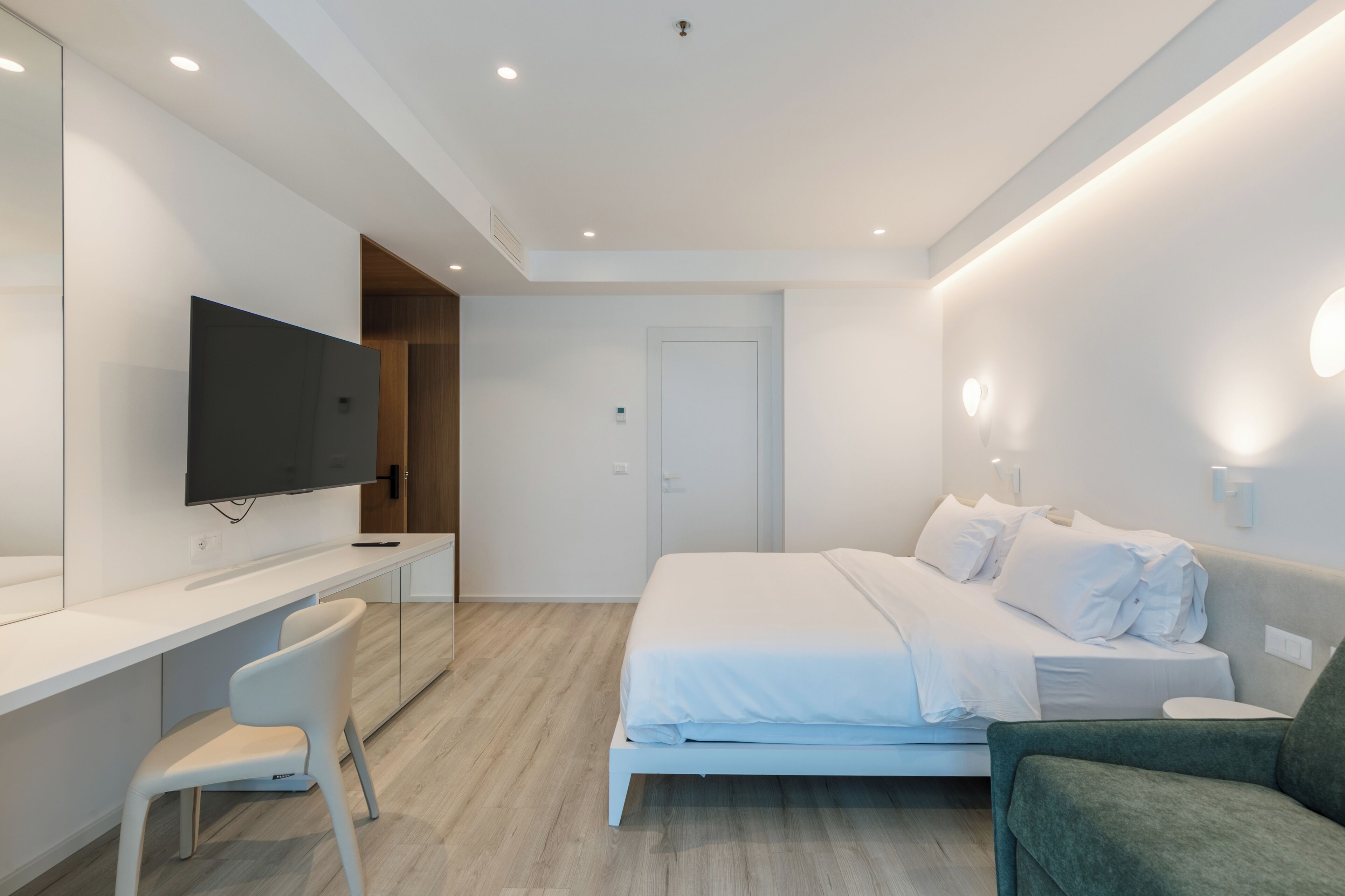 Une chambre à coucher moderne, équipée d’un lit, d’un bureau, d’une chaise, d’une télévision et d’une porte.