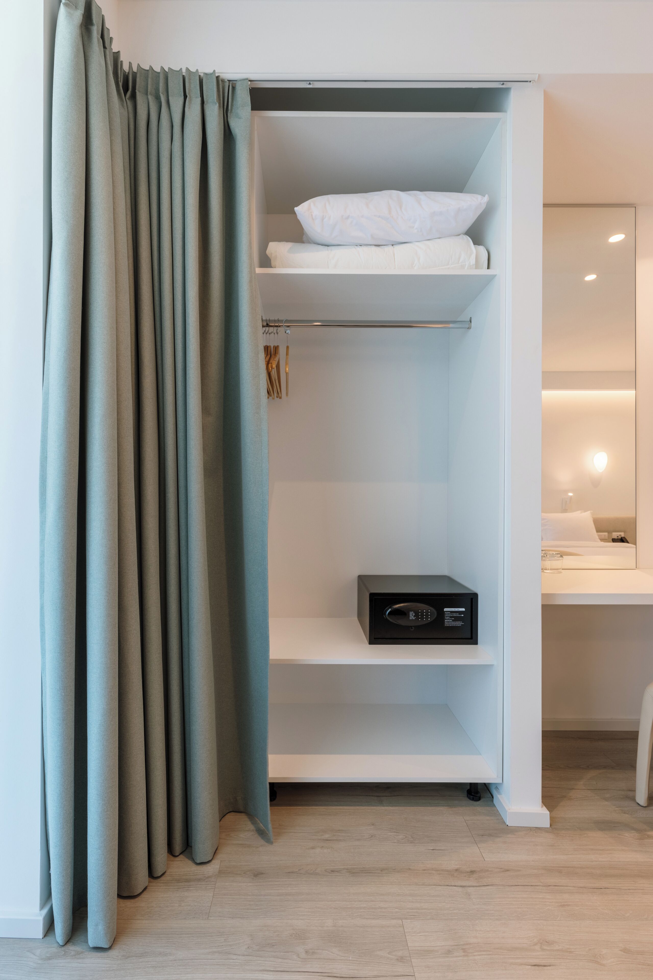 A room with a built-in closet, a flat-screen TV, and a bedside table with a lamp.