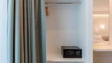 A room with a built-in closet, a flat-screen TV, and a bedside table with a lamp.