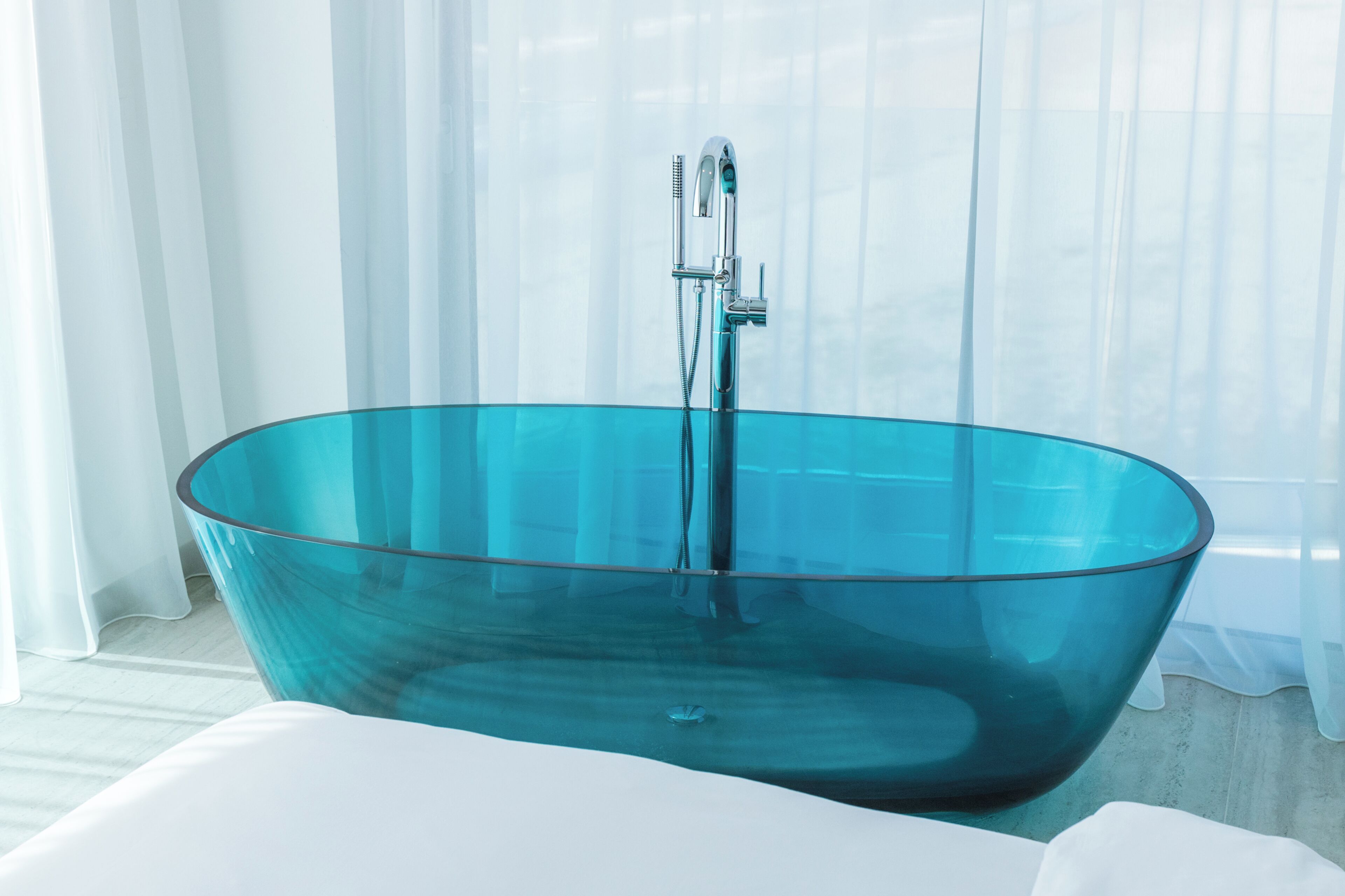A modern bathroom with a glass bathtub, a showerhead, and a white sink.