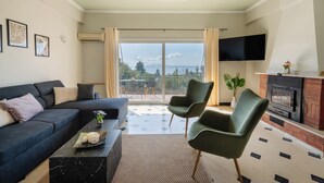 Una sala de estar con sofá, sillas, chimenea y televisor.