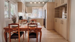 Una cocina moderna con armarios de madera, una mesa de comedor con sillas e iluminación colgante.