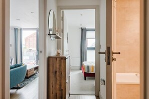 Ein Schlafzimmer mit einem Bett, einer Holzkommode, einem Spiegel und einem Fenster.