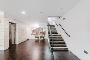 Ein modernes Interieur mit Treppe, Wandlifter und einer Sitzecke mit Sesseln.