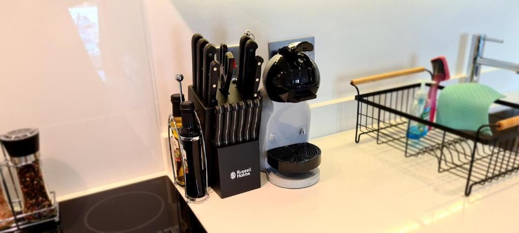 Eine Küchenarbeitsfläche mit Kaffeemaschine, einem Messerblock und einem kleinen Korb.