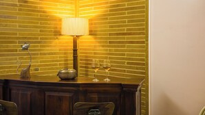 A corner of a room with a brick wall, a lamp, a decorative metal piece, and two wine glasses on a wooden counter. - Alaya Stays Abhimanyu Mansion Topaz 2BHk (Udaipur)