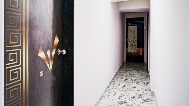 A hallway with a patterned door, a tiled floor, and a view into a room with a patterned wall. - Classic With Twin Bedspot Light Lodging (Pune)