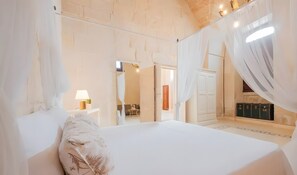 A bedroom with a large bed, a bedside table with a lamp, a mirror, and a wardrobe.