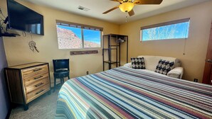 Un dormitorio con cama, cómoda, silla y ventilador de techo.