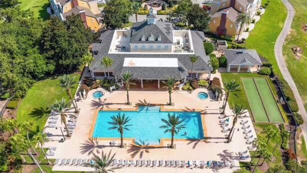 An aerial view of a resort with a central swimming pool, sun loungers, and palm trees. - Brand New Home at Reunion Resort - Near Disney (Kissimmee)