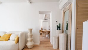 Uma sala de estar moderna com um sofá branco, piso de madeira e um espaço de jantar com cadeiras.