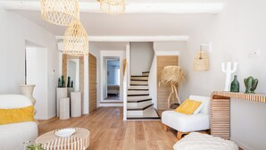 Uma sala de estar moderna com escada, piso de madeira e uma mistura de estilos de mobiliário.