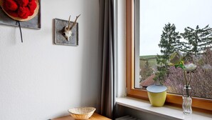 A room with a wooden table, a woven basket, a decorative skull, and a window with a view of trees and a building. - Room “Birke” with Shared Garden and Wi-Fi (Vogtsburg im Kaiserstuhl)