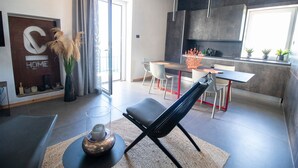 A modern kitchen with a dining area, a sofa, and a large window. - C-Home Otranto – Design Apartment with Panoramic Terrace (Otranto)