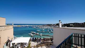A coastal town with a marina, buildings with balconies, and a clear blue sky.
