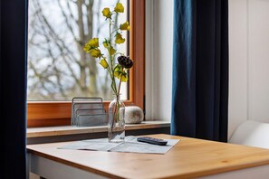 A wooden table with a vase of yellow flowers, a remote control, and a white pumpkin on a windowsill. - Room 'In Vino Veritas' with Shared Garden and Wi-Fi (Vogtsburg im Kaiserstuhl)