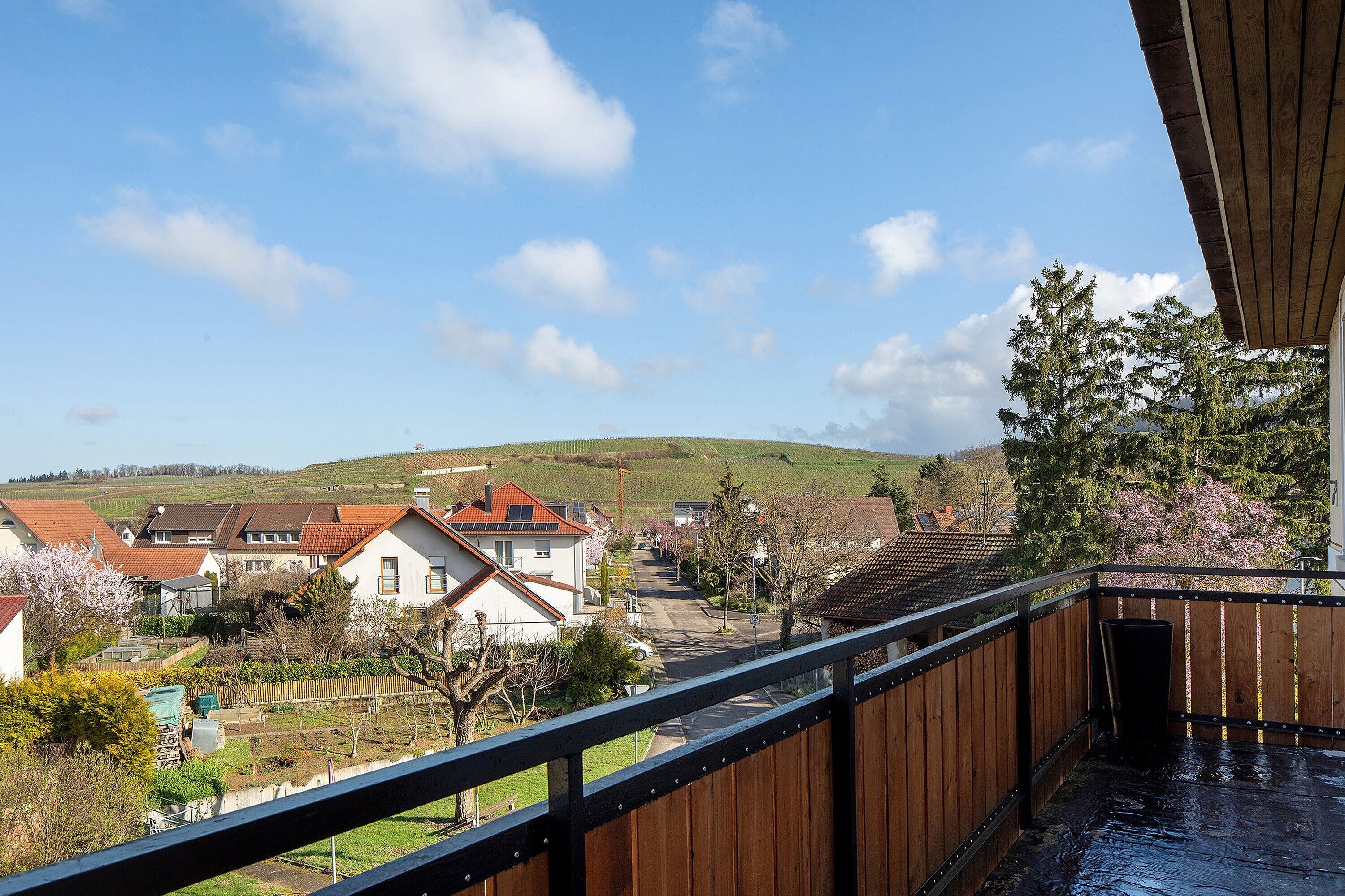 A residential area with houses, a wooden balcony, and a clear sky.