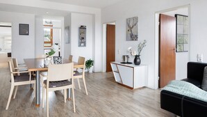 Um espaço de estar moderno com área de jantar, sofá, mesa de centro e um quadro na parede.