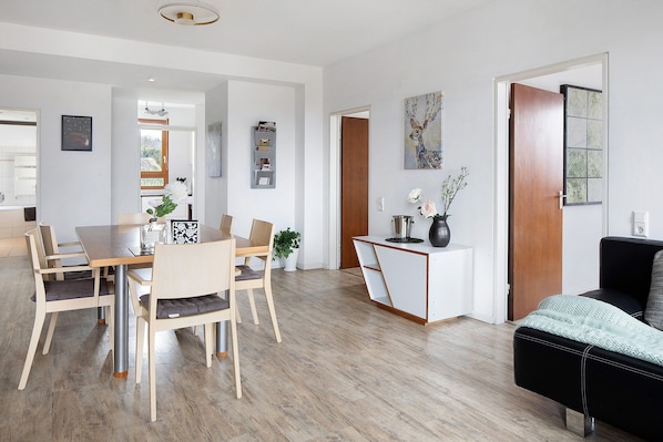 A modern living space with a dining area, a sofa, a coffee table, and a painting on the wall.