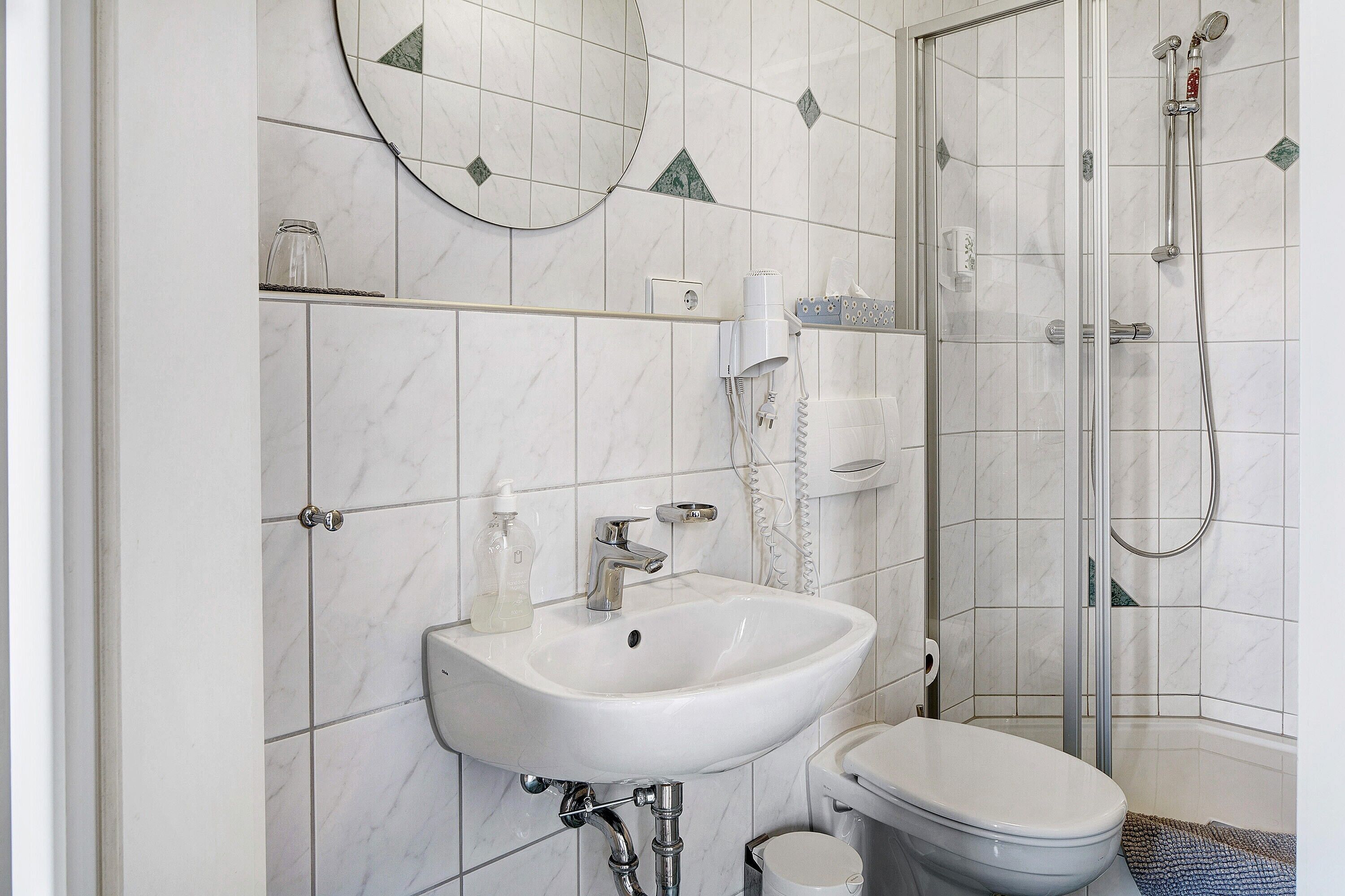 Een badkamer met een witte wastafel, toilet en douche.