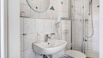 Een badkamer met een witte wastafel, toilet en douche.