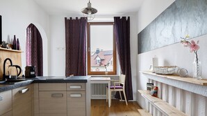 Una cocina moderna con una isla central, una zona de comedor con una silla y vistas por una ventana.