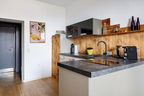 A modern kitchen with a wooden cabinet, a black countertop, and a built-in oven.