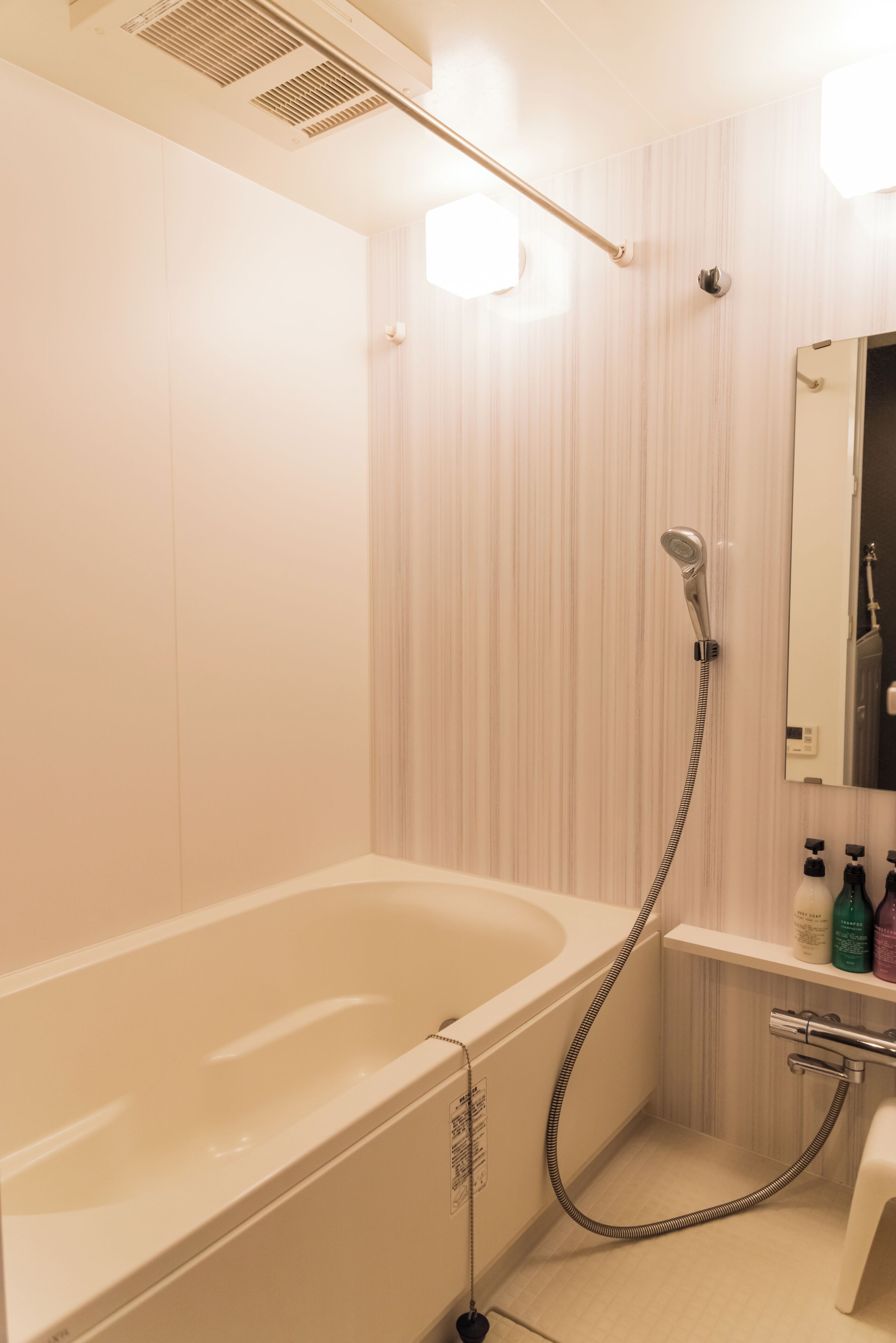 Une salle de bain équipée d’une baignoire, d’une douche, d’un miroir et d’une étagère où sont rangés les articles de toilette.