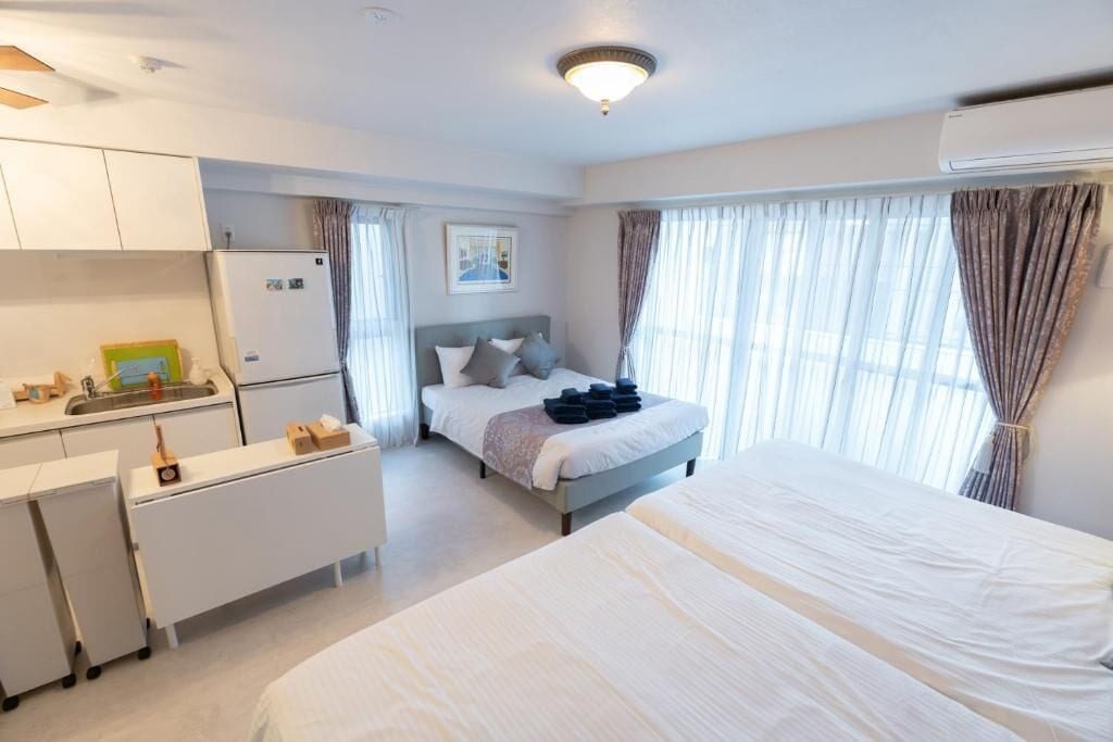 Camera d'albergo con un letto, una scrivania, angolo cottura e un'ampia finestra con tende.