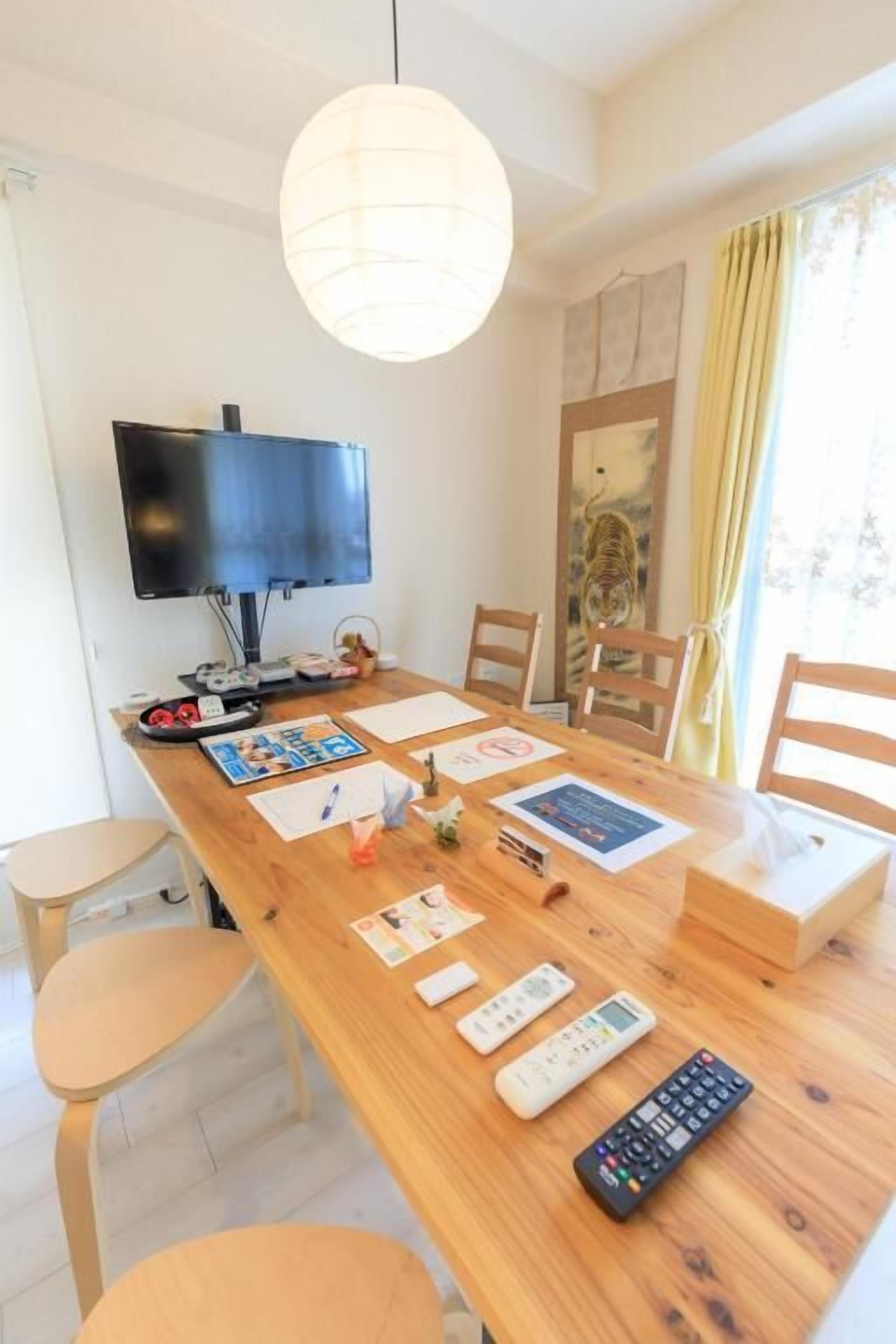 A wooden dining table with chairs, a television, and various remote controls.