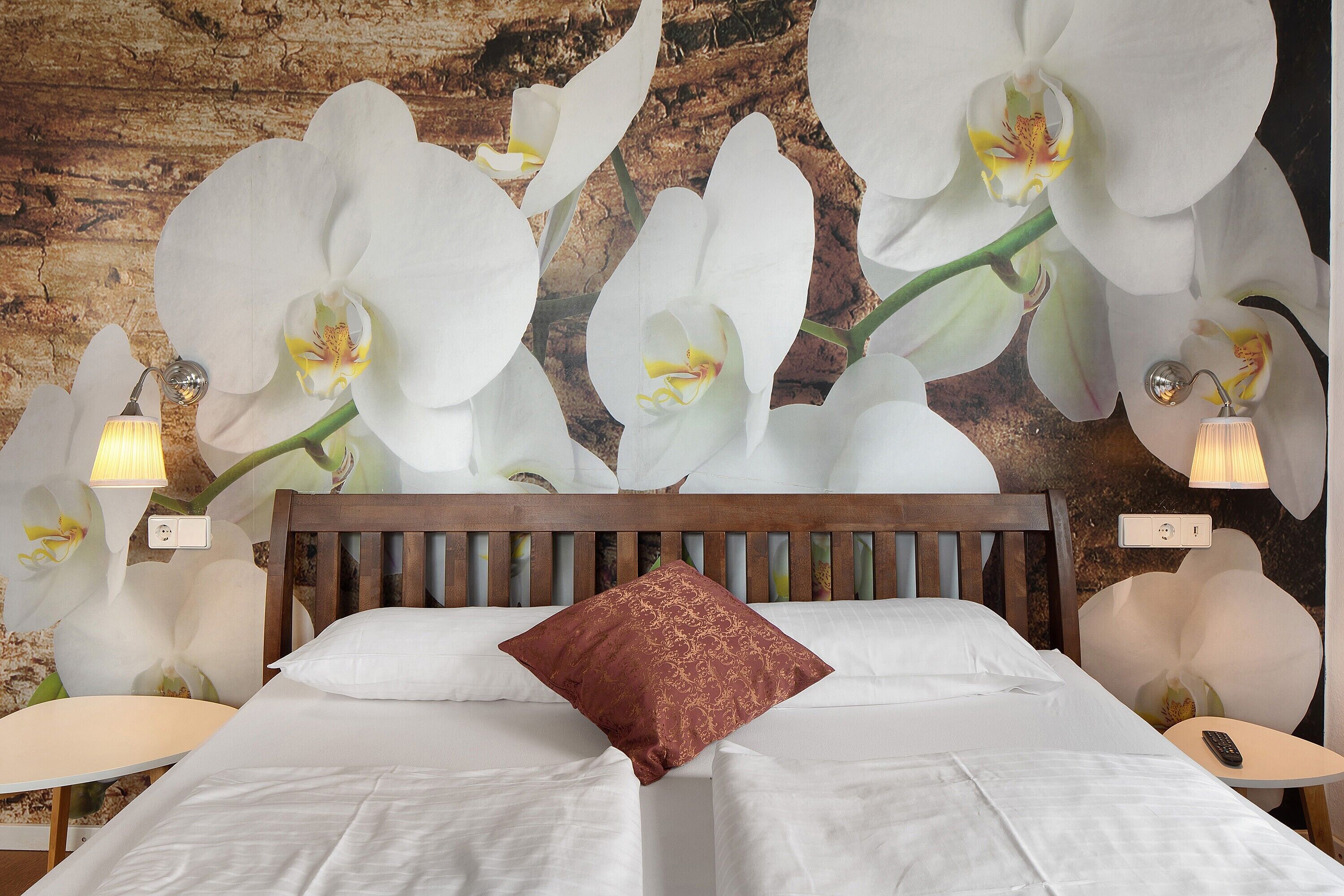 A bed with white linens, a wooden headboard, and a brown decorative pillow.