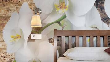 Quarto com cabeceira de madeira, travesseiro branco e luminária fixada na parede.