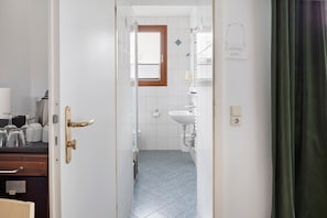 Ein Badezimmer mit Dusche, Waschbecken und Fenster.