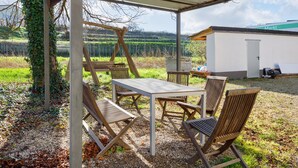 Un área de estar al aire libre con una mesa y sillas, una estructura de pérgola y un edificio con la inscripción 'Markt' al fondo.