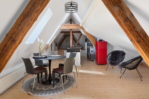 Une pièce de style loft comprenant un coin repas, une cuisine et un meuble rouge.