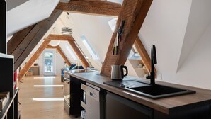 Una cocina moderna con vigas de madera, un lavamanos negro y encimera de madera.