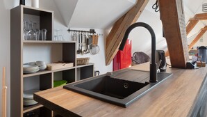 Una cocina moderna con un lavamanos negro, estantes de madera y una variedad de utensilios de cocina.