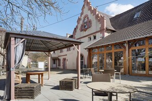 En innergård med utomhusmöbler, en pergola och en byggnad med en distinkt arkitektonisk stil.