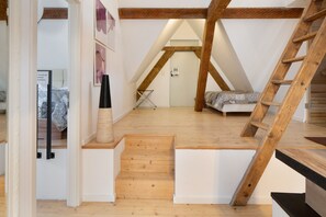 Una stanza in stile loft con una scala in legno, un letto e una scala a pioli.